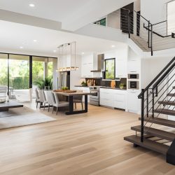 Stylish spacious kitchen and living room with refrigerator and washing machine overlooking cozy dining area with wooden ceiling next to open balcony on sunny day. Concept of modern design solutions